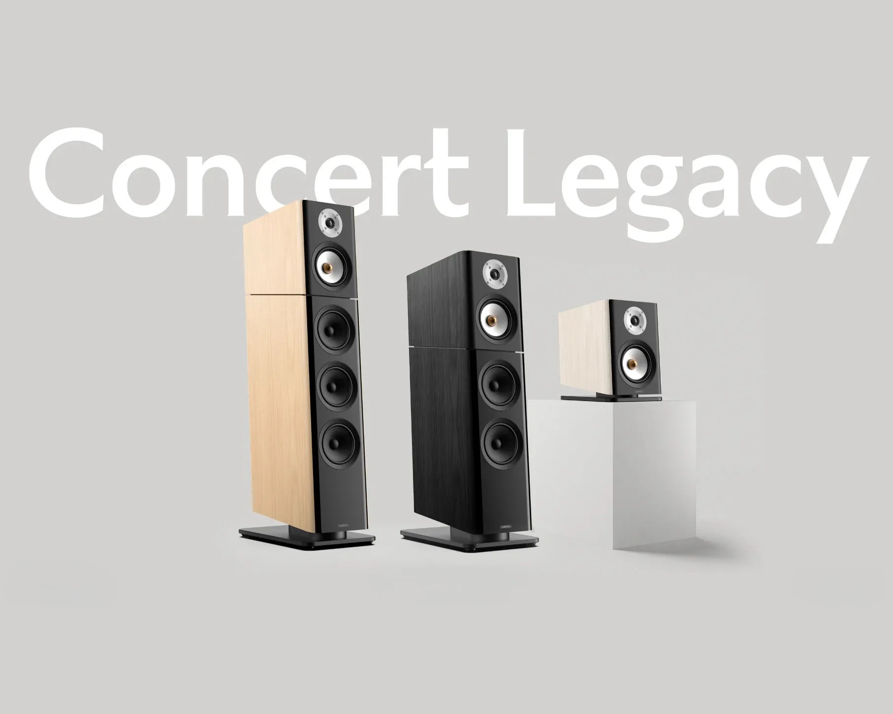 Three modern floor-standing and bookshelf speakers in light wood and black finishes on a gray background with "Concert Legacy" text.