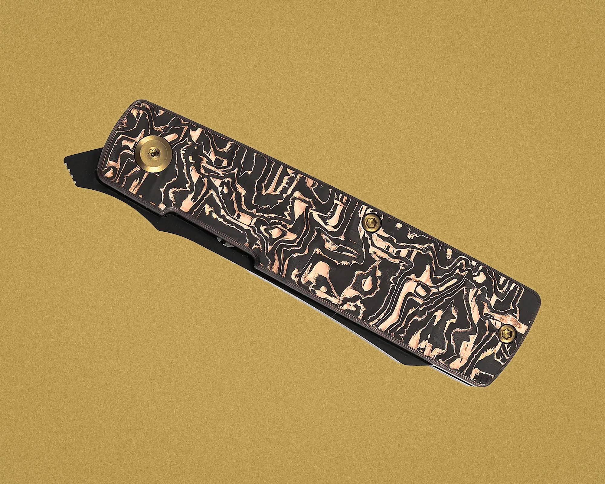 Close-up of a folding knife handle with a black and copper marbled pattern and brass screws on a gold background.