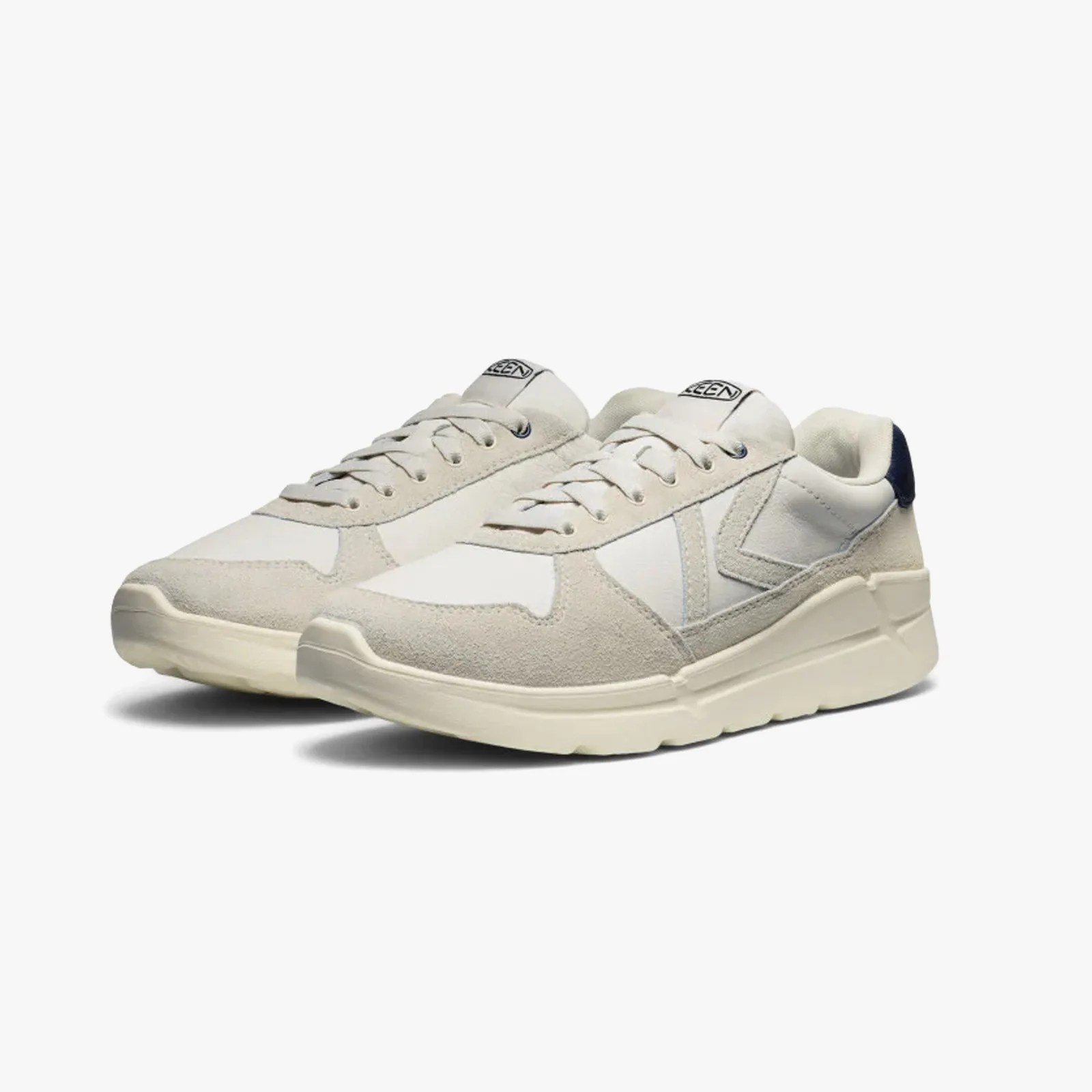 Pair of off-white suede and fabric sneakers with cream soles and navy heel accents.