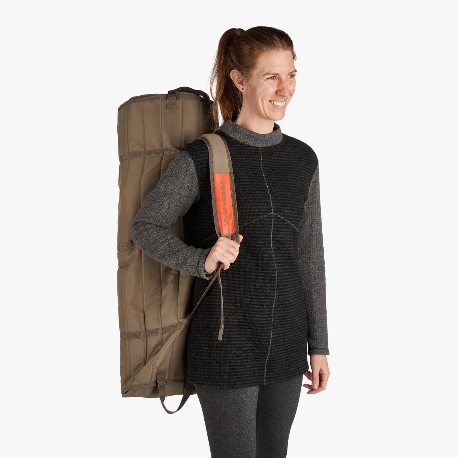 Woman wearing a black and gray long-sleeve top carrying a large olive green padded bag with a shoulder strap.