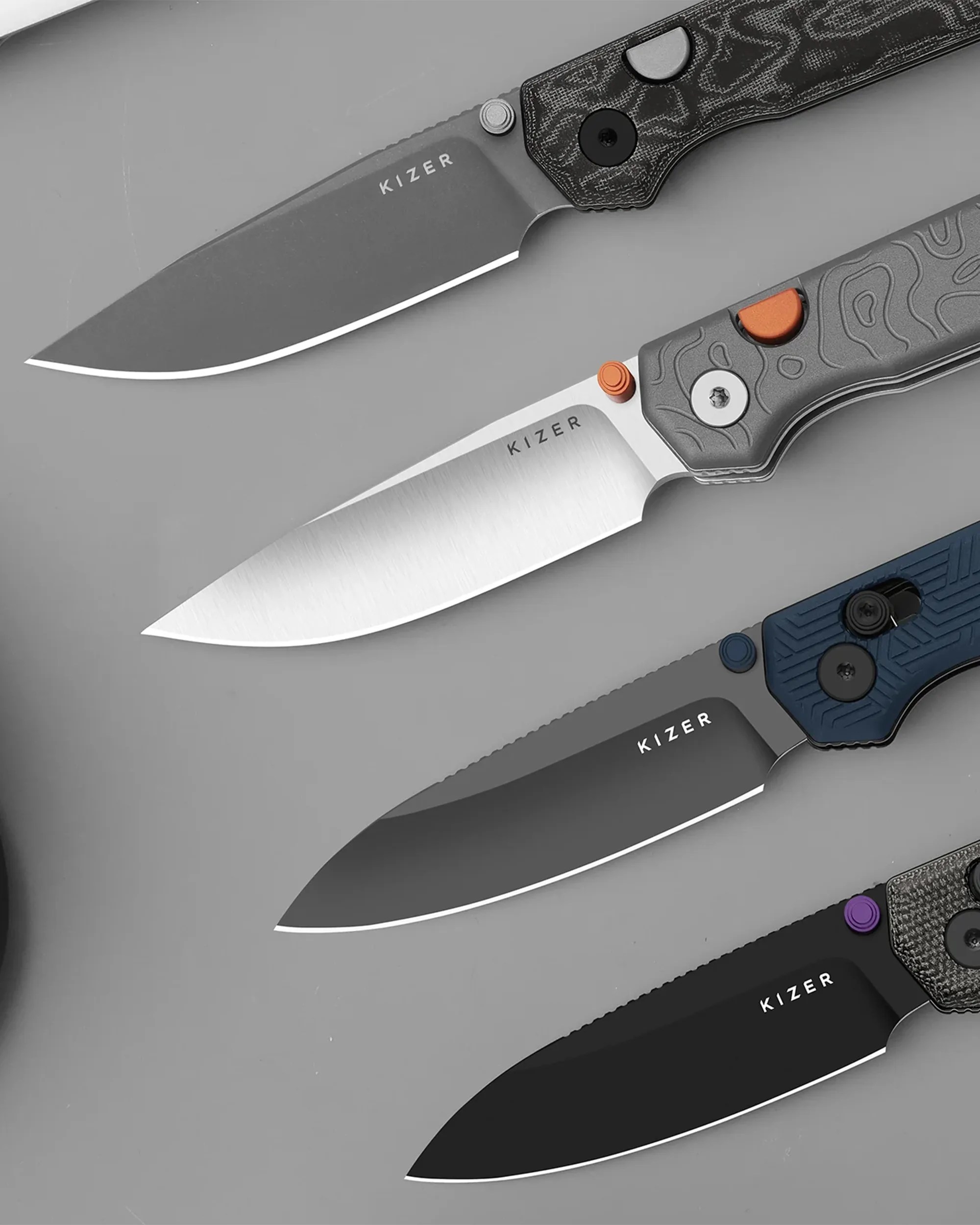 Four Kizer folding knives with different blade finishes and handle colors arranged diagonally on a gray surface.