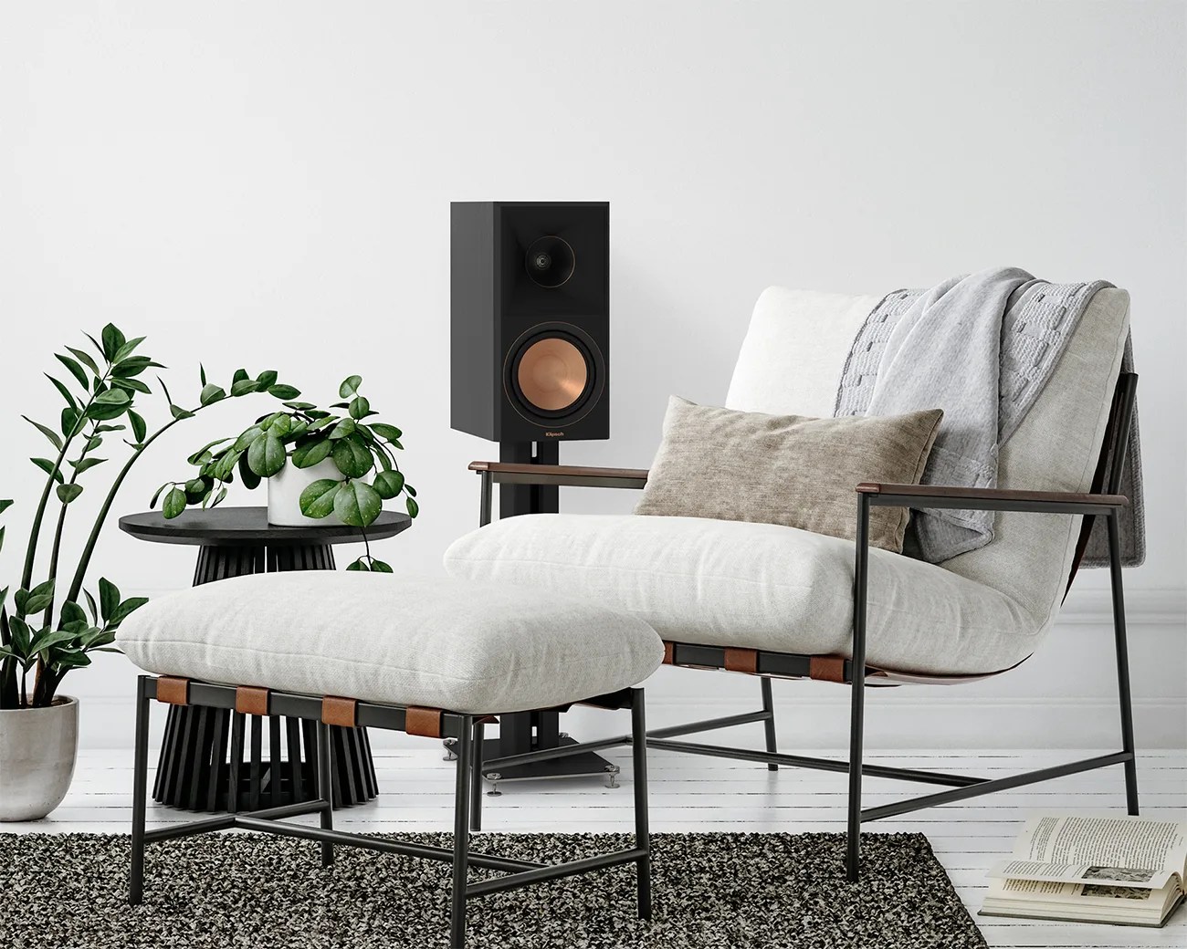 Light gray cushioned armchair with matching ottoman, black metal frame, beige pillow, and gray throw in a modern living room.