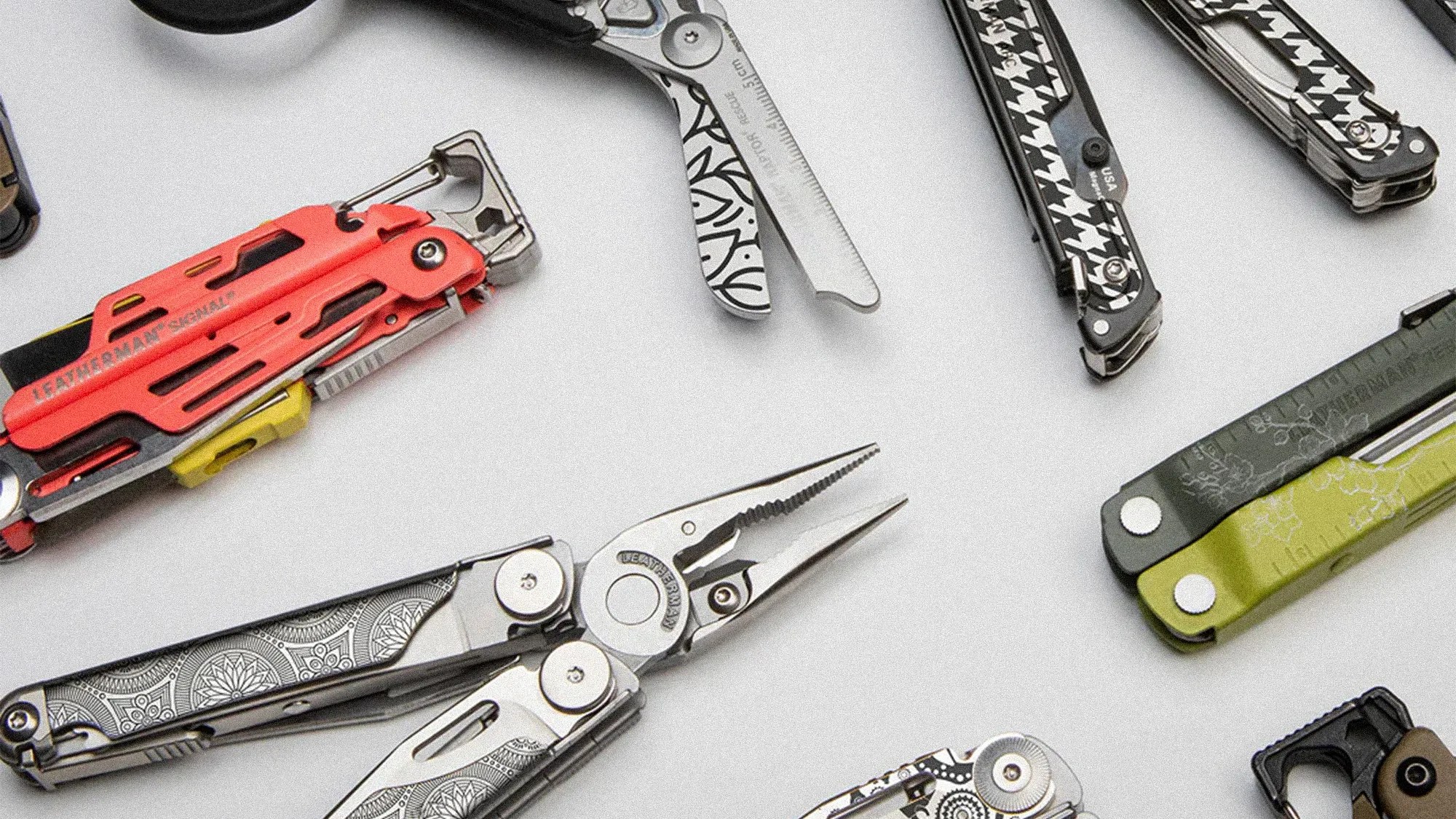 Collection of various Leatherman multi-tools with different colors and patterns on a white surface.