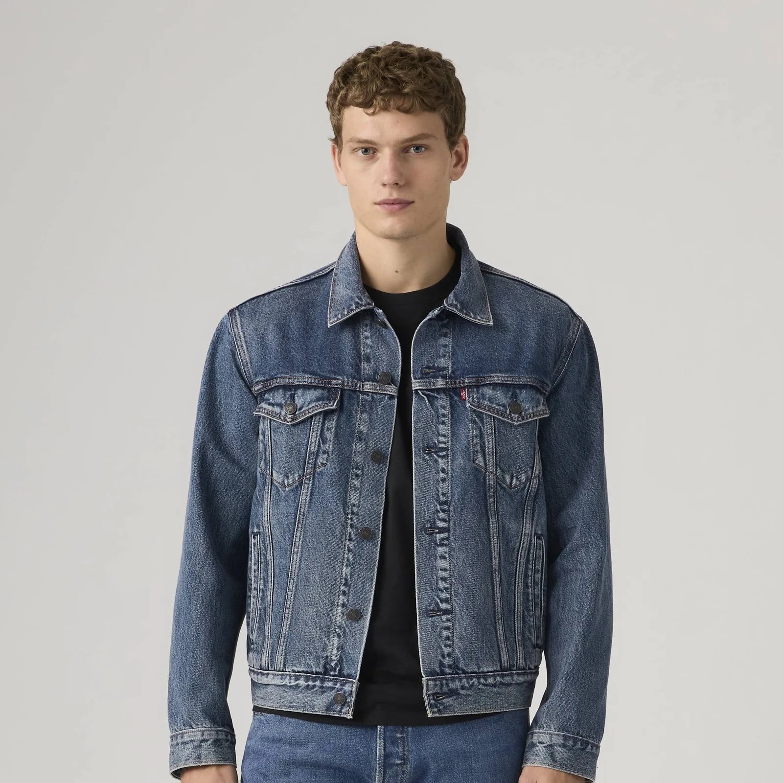 Blue denim jacket with buttoned chest pockets worn over a black shirt.
