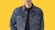 Blue denim jacket with buttoned chest pockets worn over a black shirt against a yellow background.