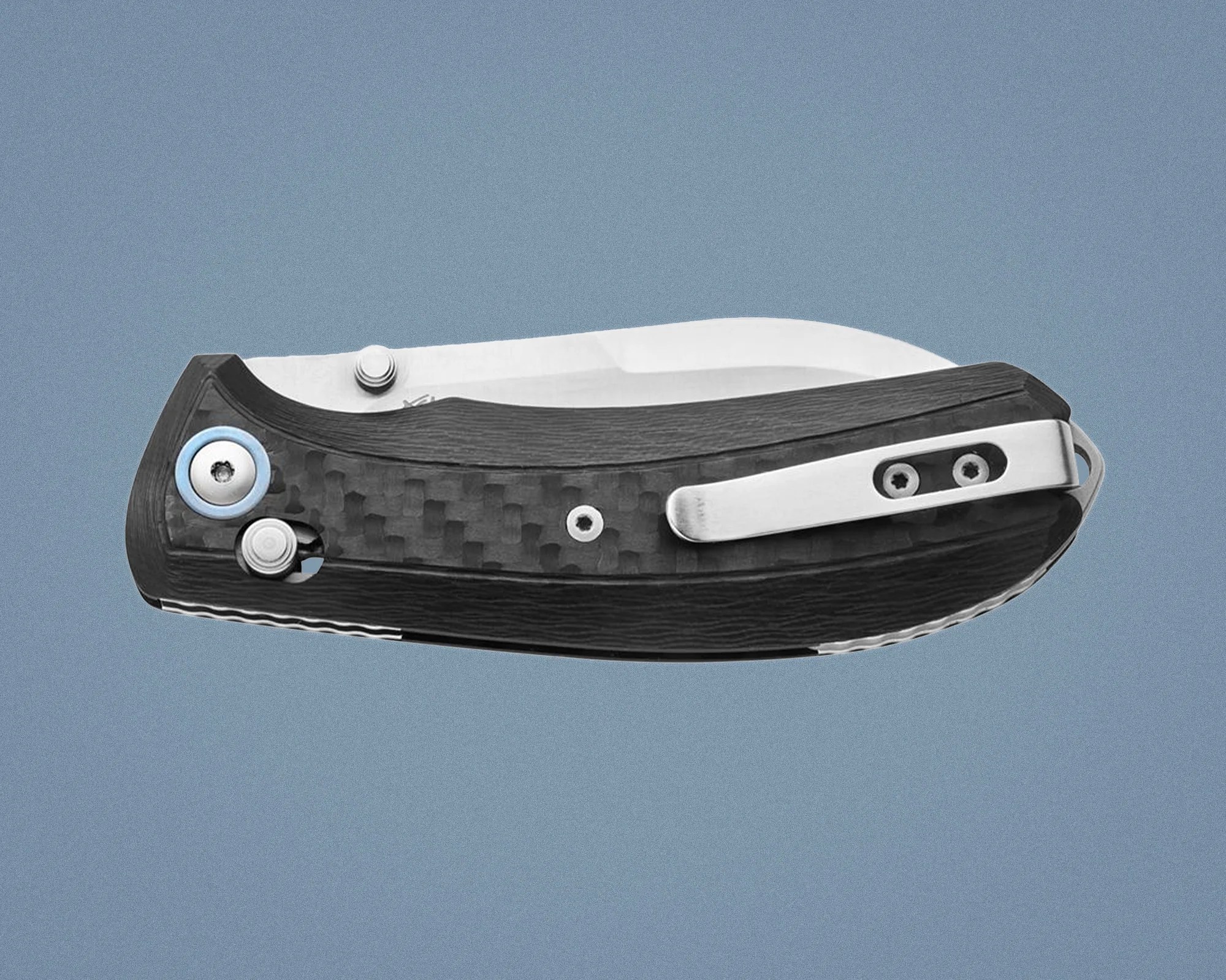 Folded pocket knife with carbon fiber handle and silver metal clip on a blue background.
