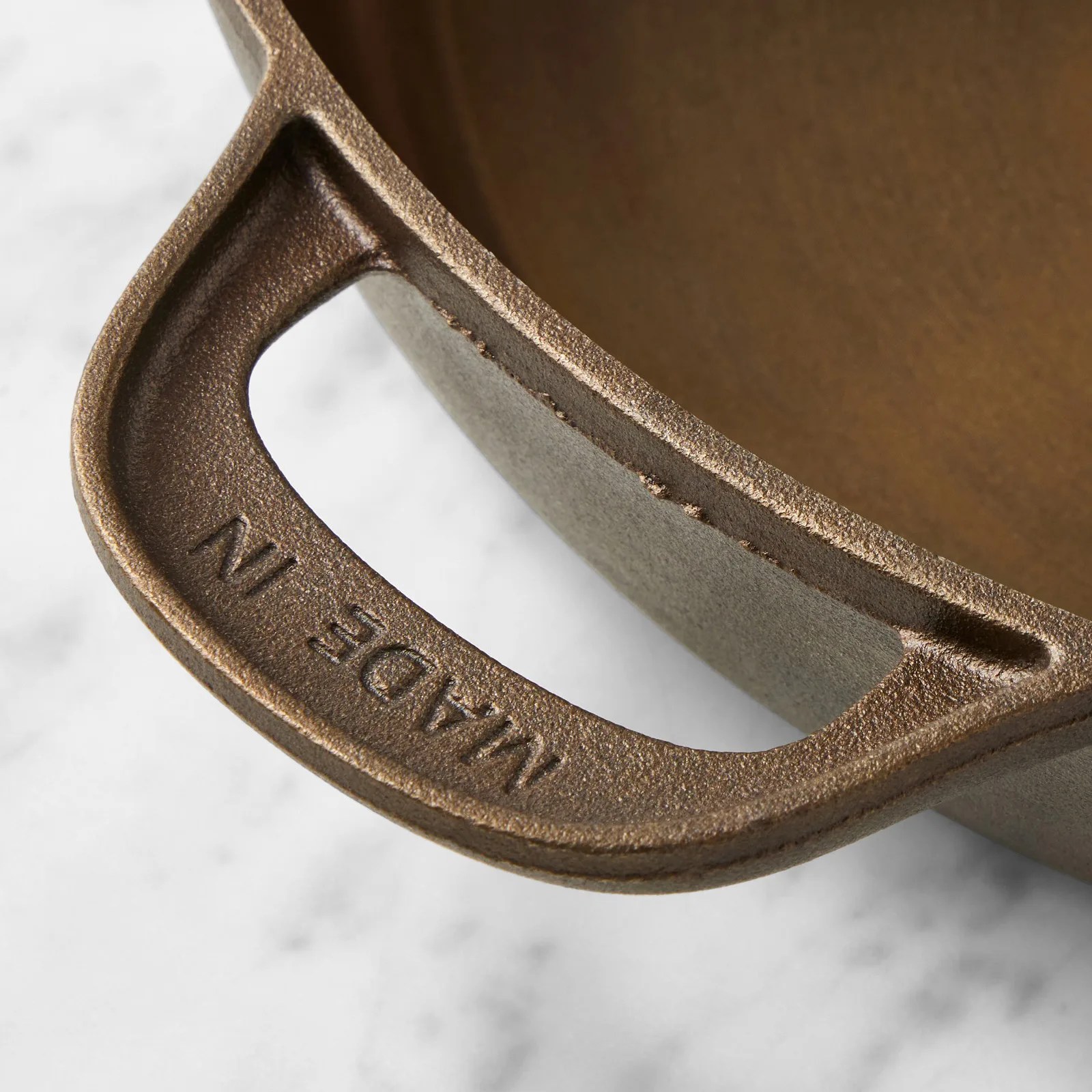 Close-up of a rough-textured cast iron handle with "MADE IN" embossed on it.