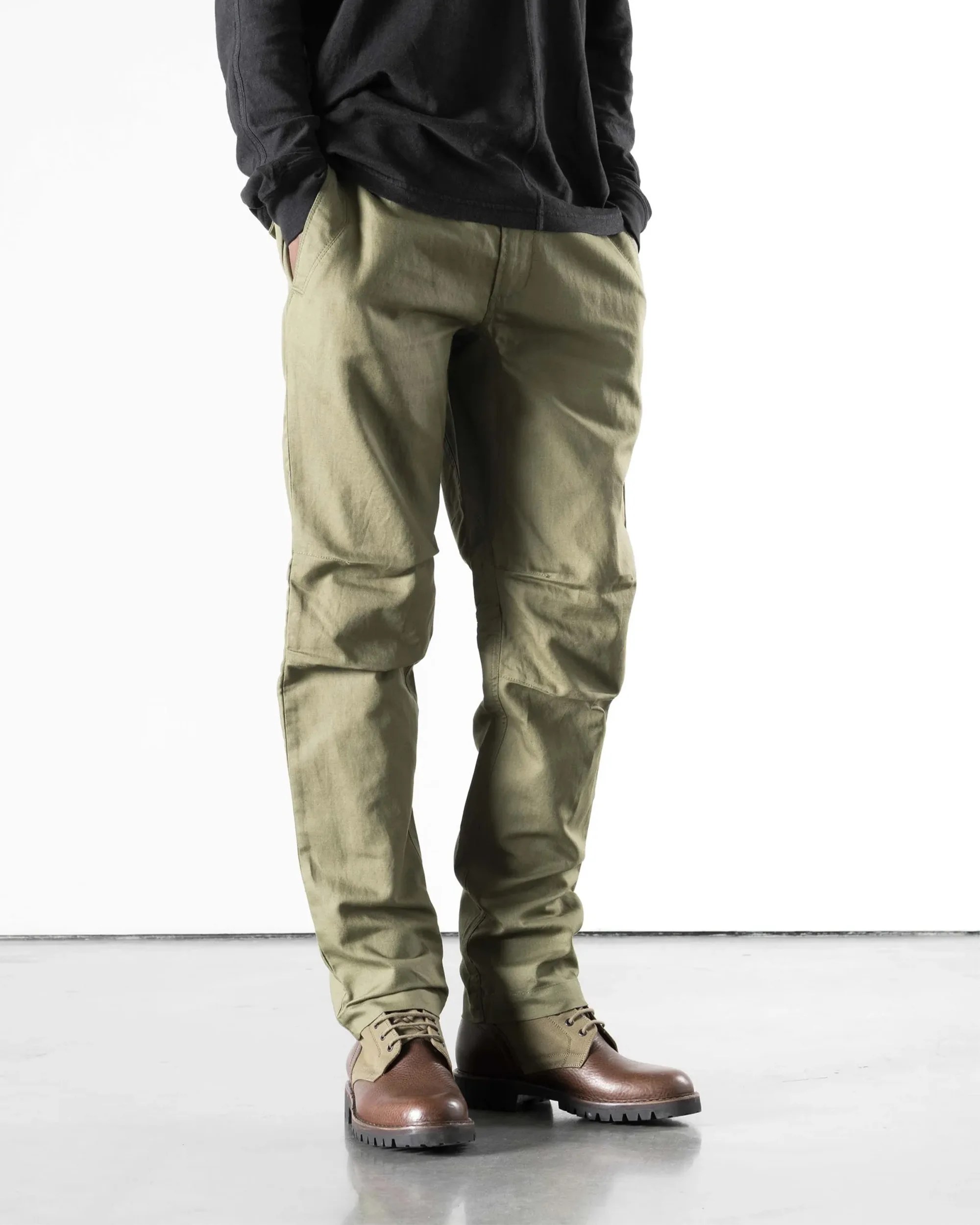 Light olive green pants paired with brown leather boots on a gray floor.