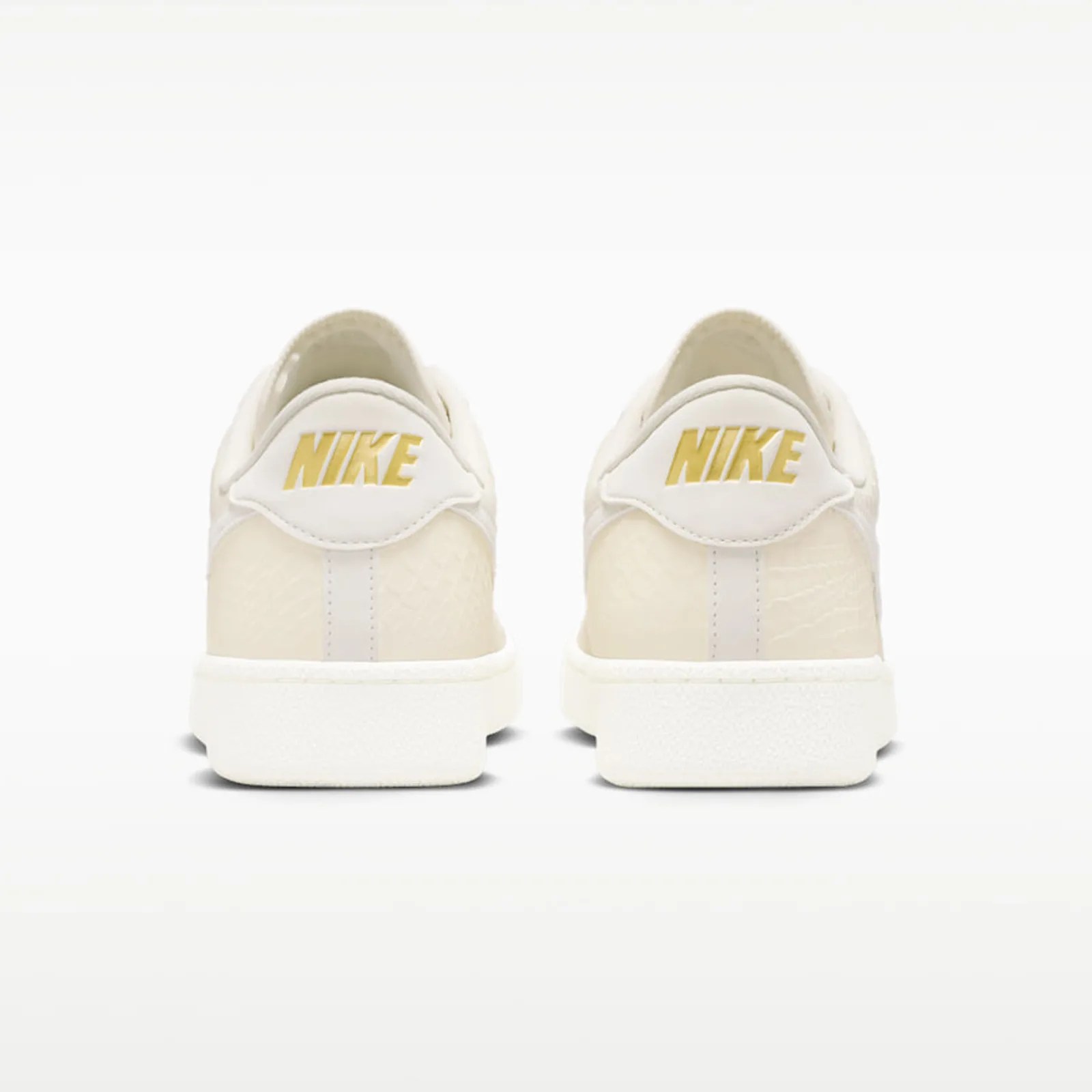 Pair of off-white Nike sneakers shown from the back with gold Nike logo on the heel tab.