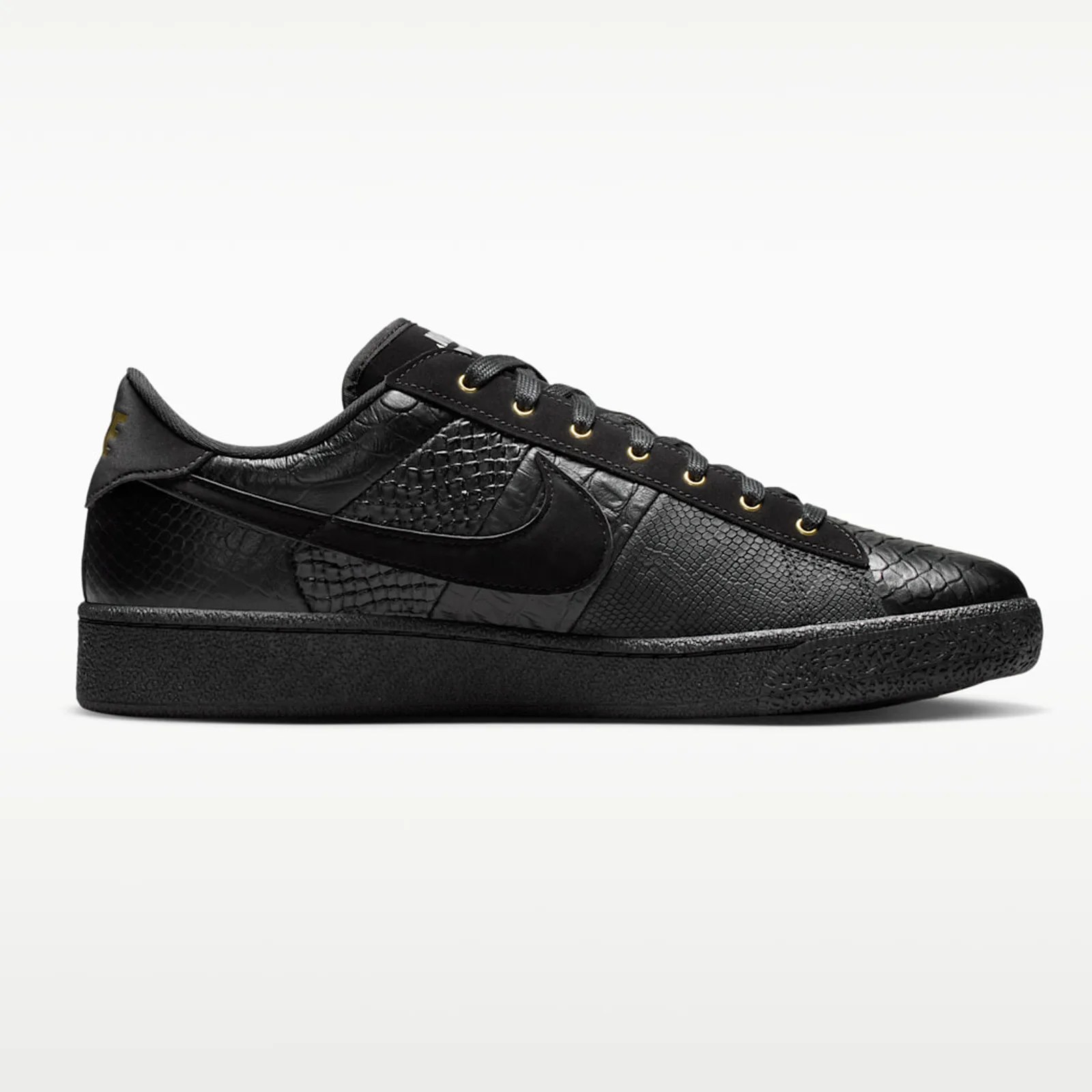 Black low-top sneaker with textured leather panels and gold eyelets.