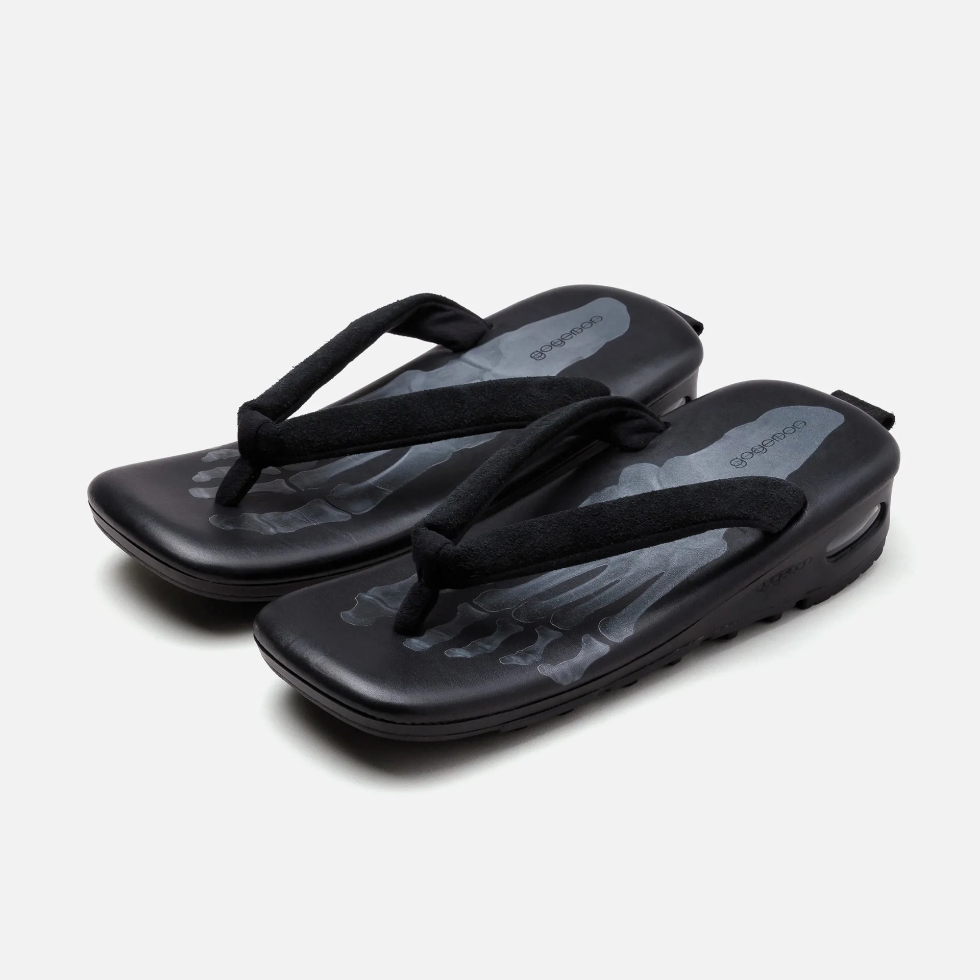 Black flip-flops with padded fabric straps and a gray skeletal foot print on the footbed.