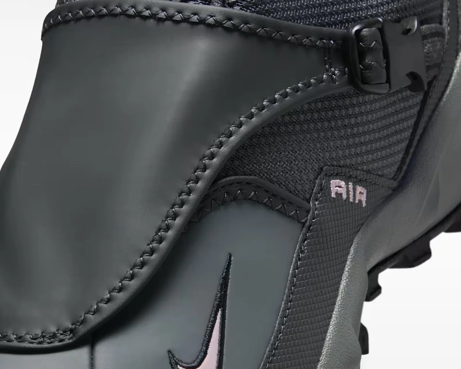 Close-up of a black and gray Nike shoe with visible stitching, a pink Nike swoosh, and "AIR" text.