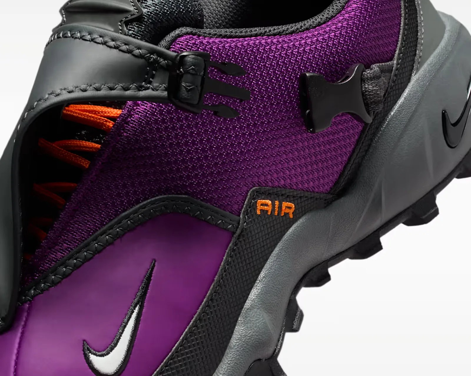 Close-up of a purple and black Nike Air sneaker with orange laces and a gray sole.