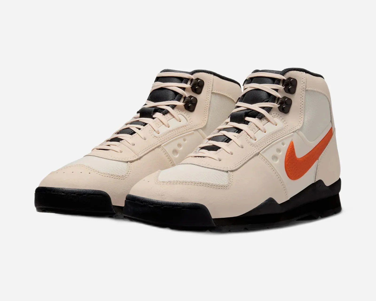 Pair of beige high-top sneakers with black soles, black tongue, and orange Nike swoosh logo on the side.