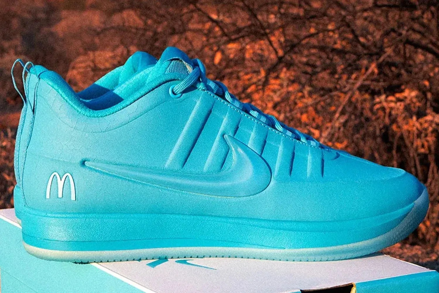 Bright blue Nike sneaker with a white McDonald's logo on the heel, placed on a matching blue and white box.