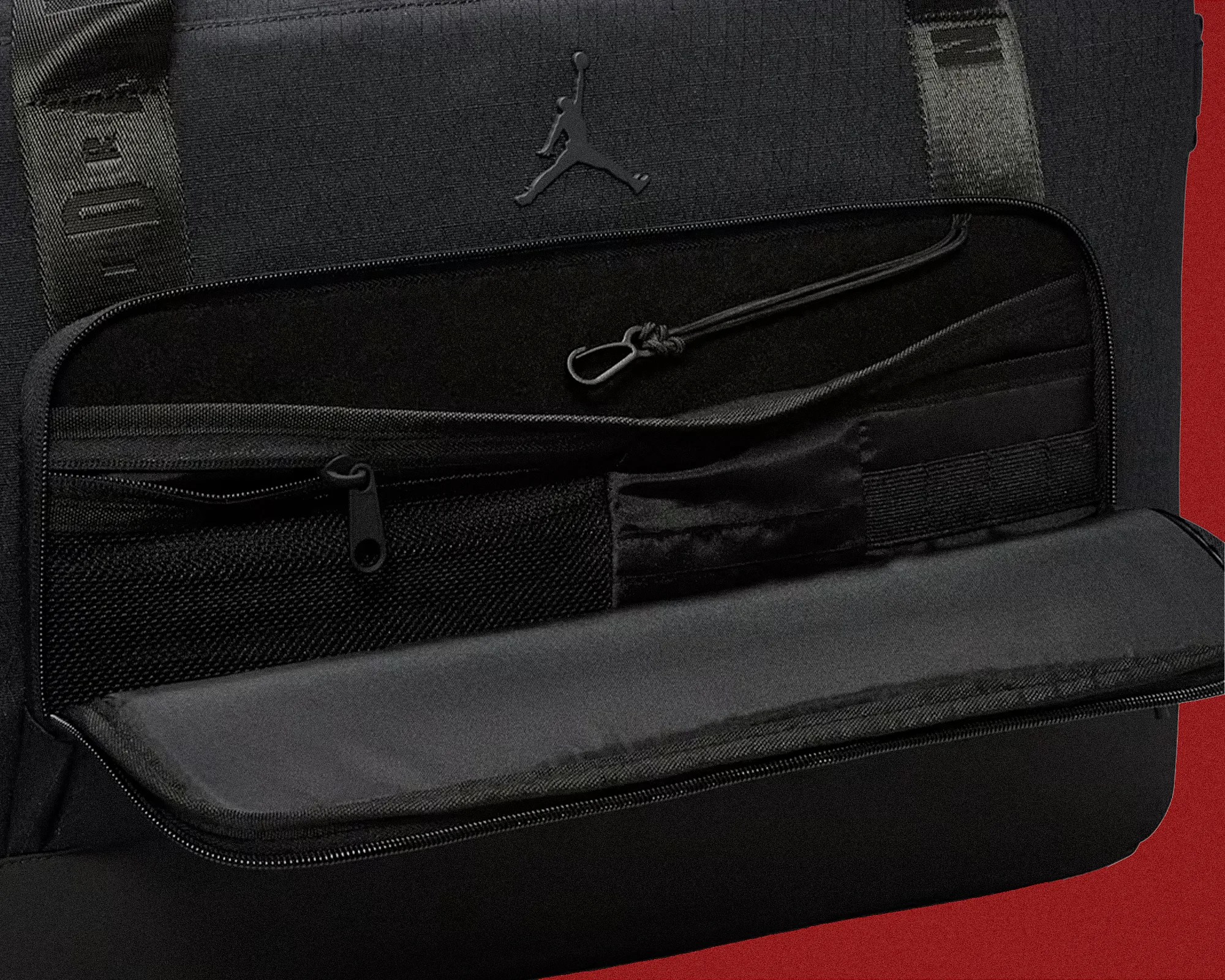 Black Jordan backpack interior with multiple zippered and elastic pockets and a black Jumpman logo.