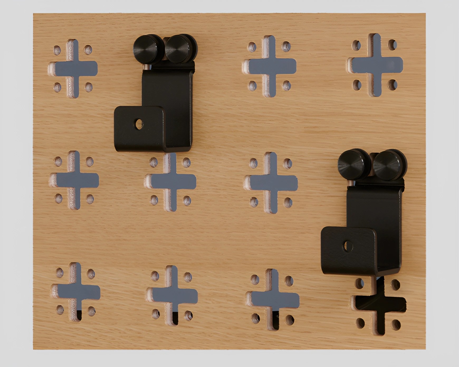 Light wood panel with multiple cross-shaped cutouts and two black metal hooks attached.