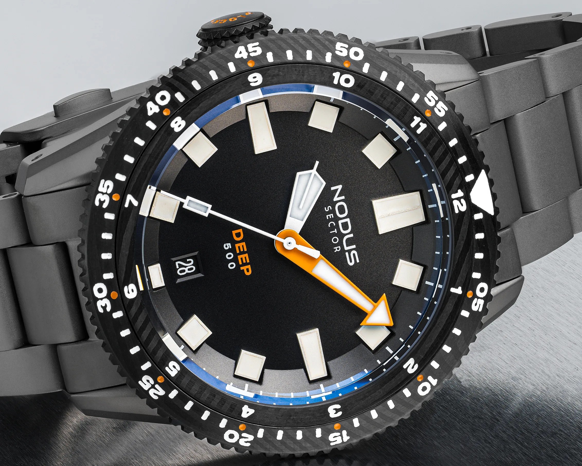 Black dive watch with orange and white hands, white hour markers, and a gray metal bracelet.