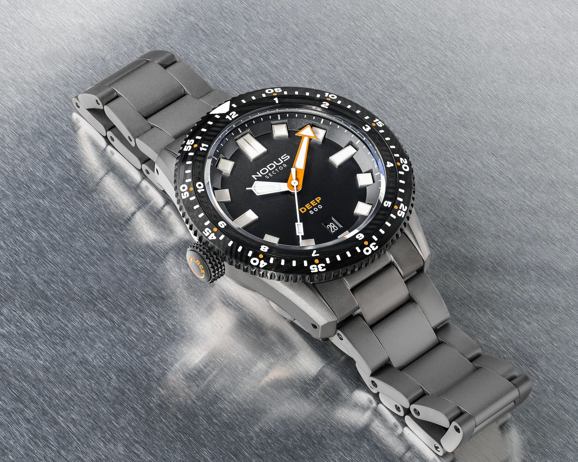 Black dial Nodus Sector Deep 500 dive watch with orange accents and gray metal bracelet on brushed metal surface.