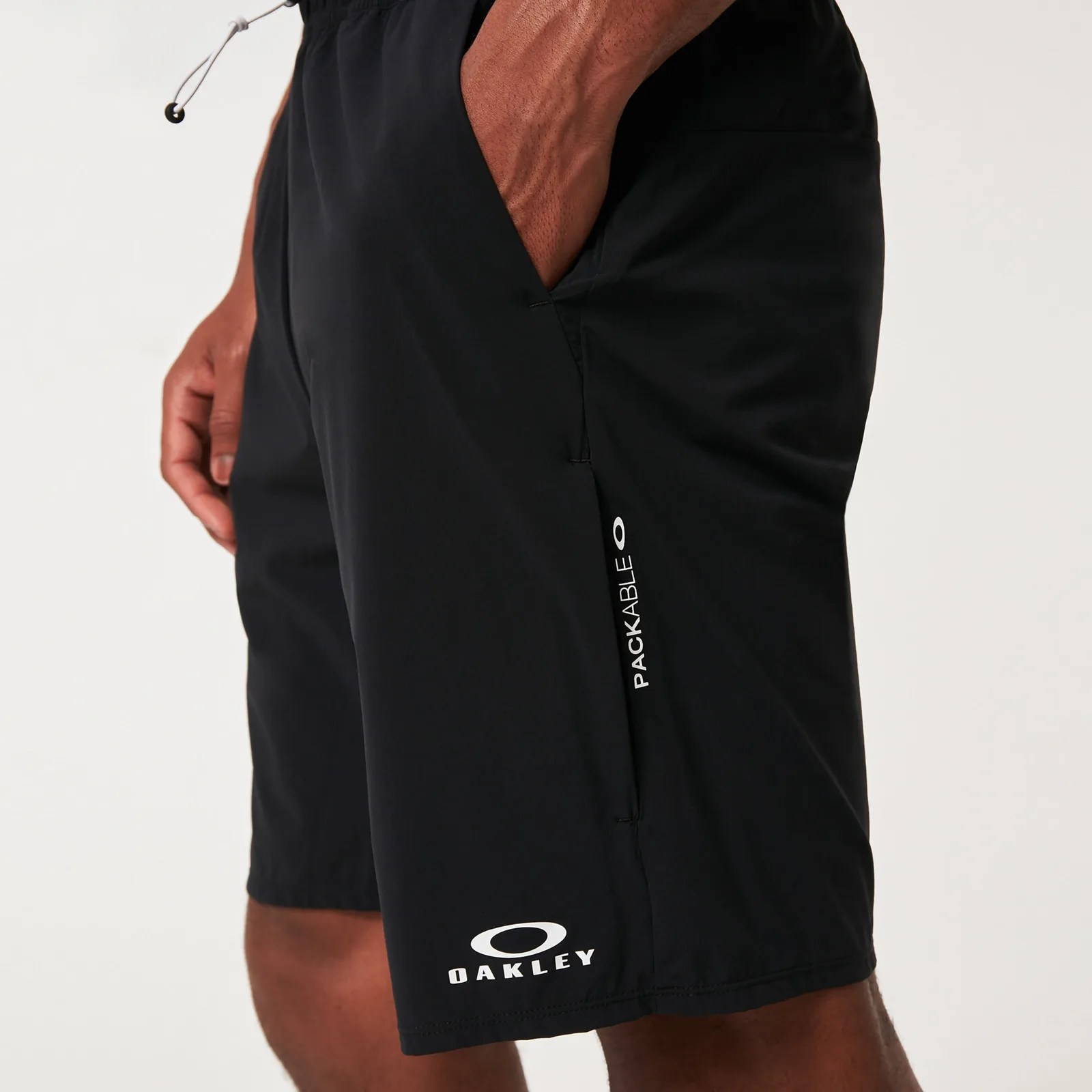 Black Oakley packable shorts worn by a person with hand in pocket.