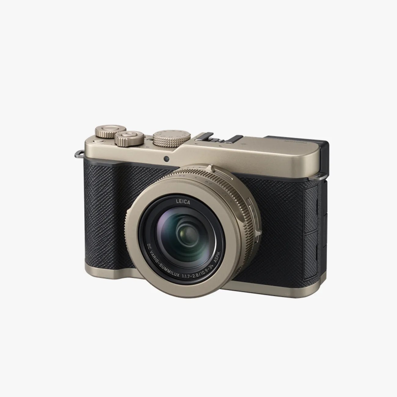 Compact digital camera with black textured grip and champagne gold metal top and lens barrel.