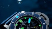 Close-up of a Panerai Submersible watch with blue bezel, luminous green hour markers, and a blue minute hand.