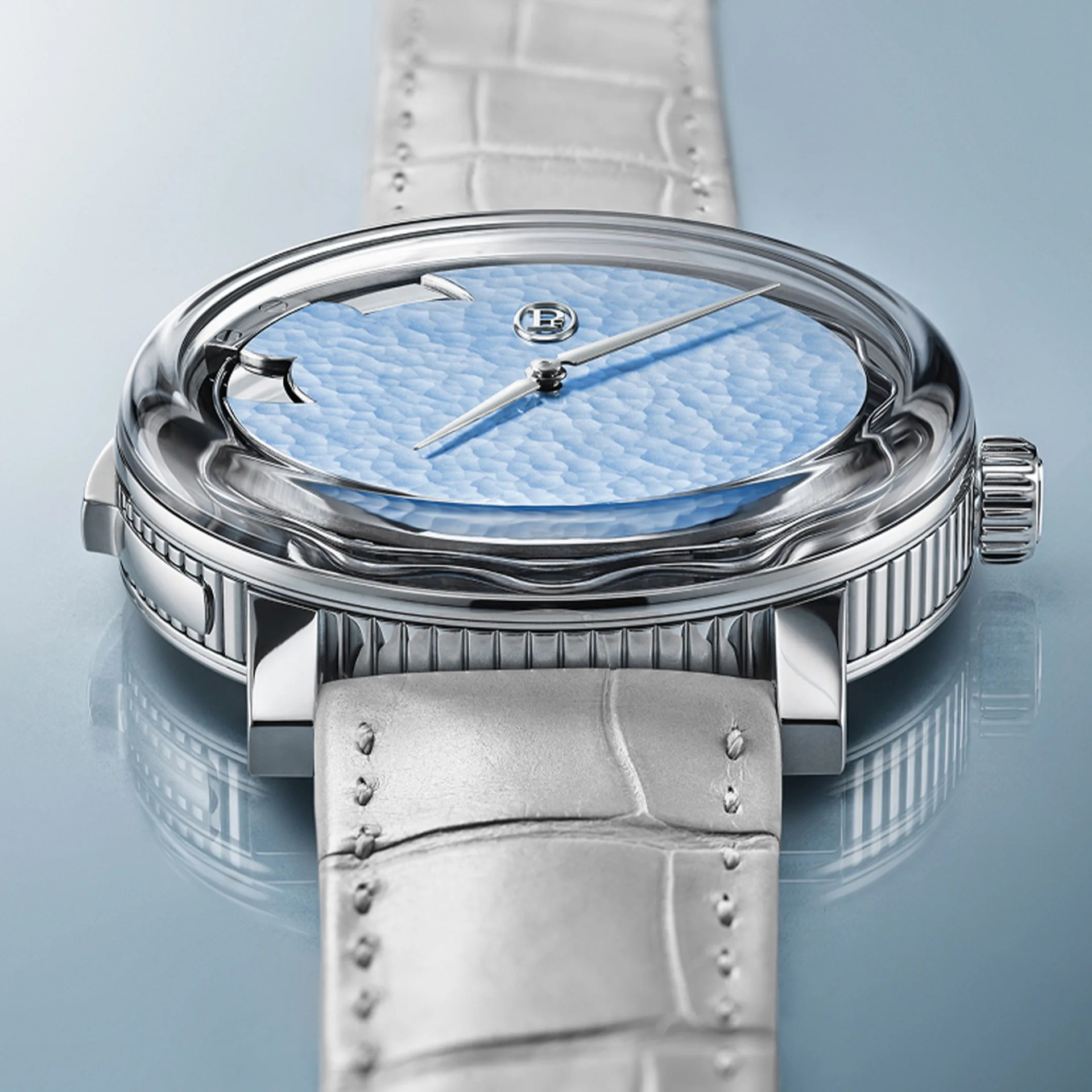 Silver wristwatch with a textured light blue dial and white leather strap on a reflective surface.