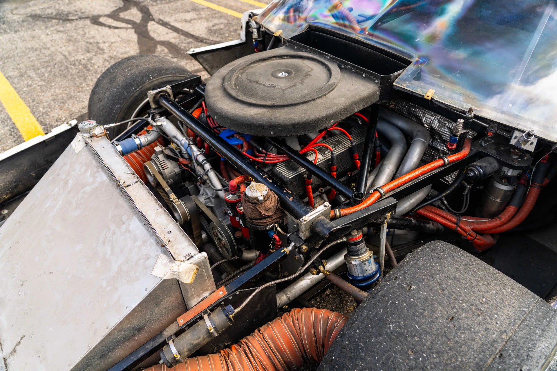 Close-up of a race car engine bay showing a Ford Motorsport engine, air filter, belts, and suspension components.