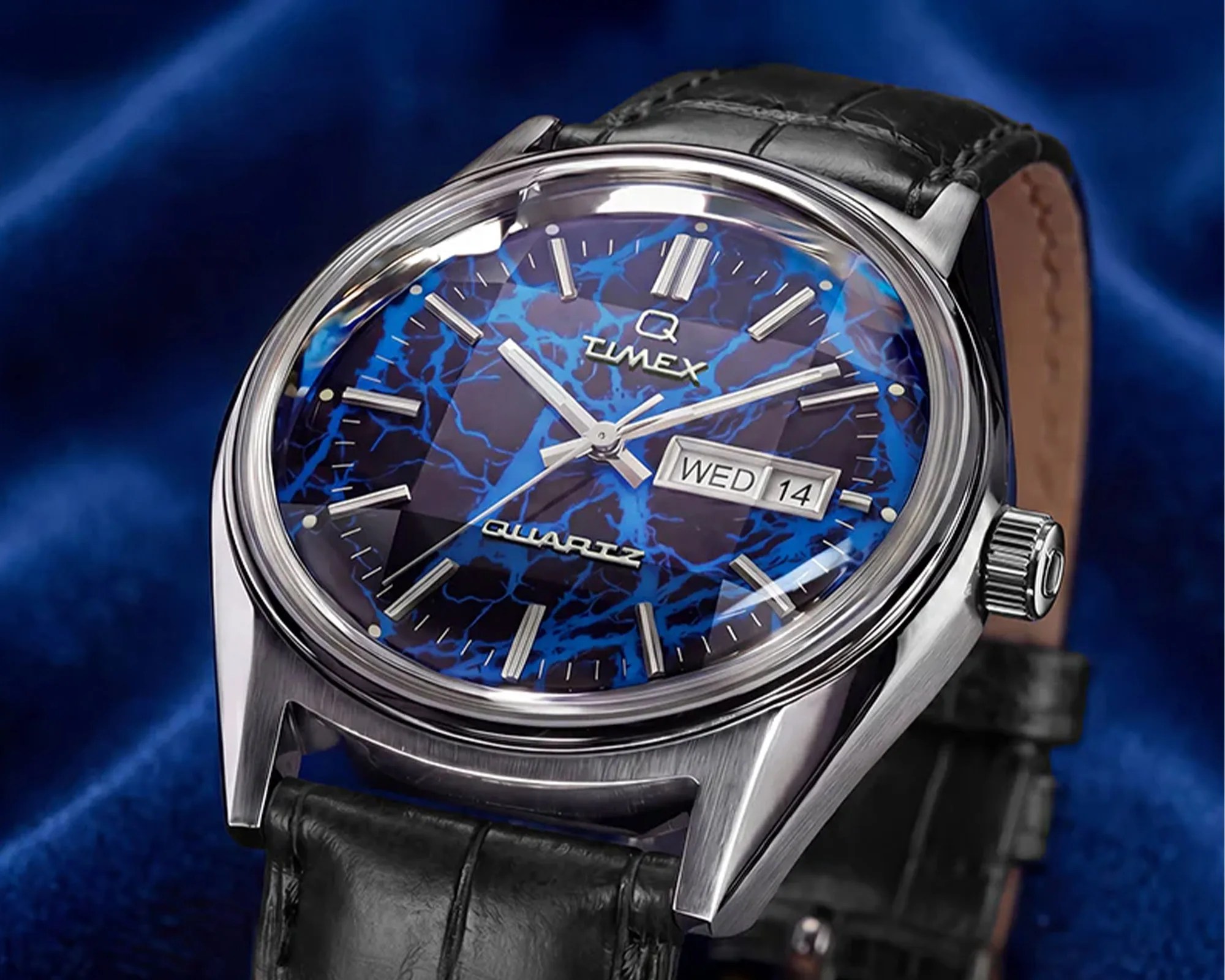 Timex Q Quartz wristwatch with blue marbled dial, silver markers, date display, and black leather strap.