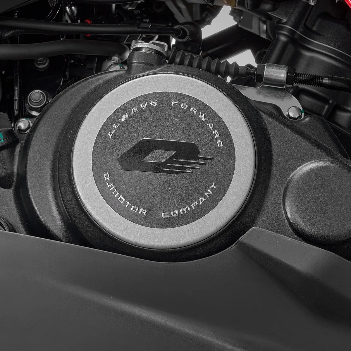 Close-up of a black and silver motorcycle engine cover with "Always Forward QJMOTOR Company" text and logo.
