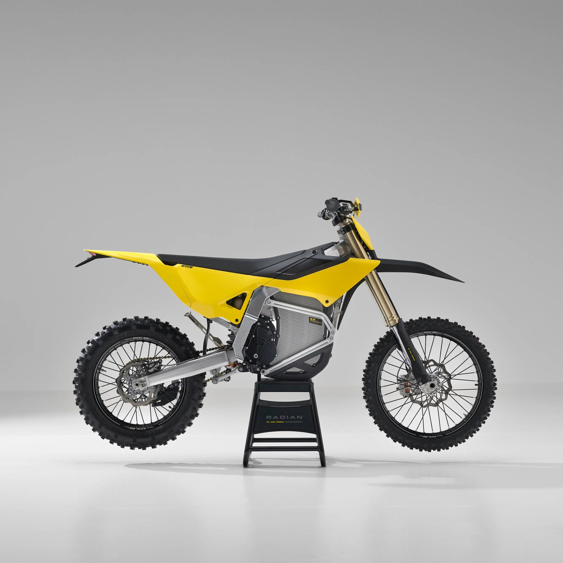 Yellow and black electric dirt bike on a black stand against a gray background.
