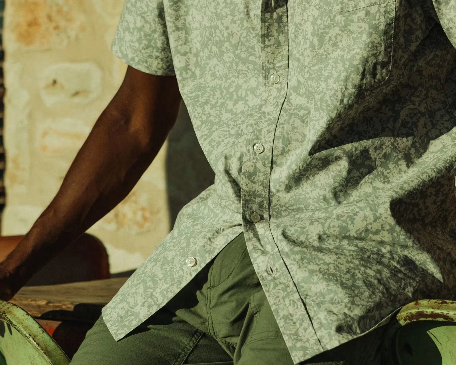 Light green short-sleeve button-up shirt with a subtle floral pattern worn with olive green pants.