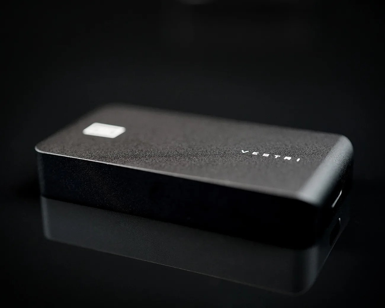 Black rectangular Vestri-branded electronic device with rounded edges on a reflective black surface.