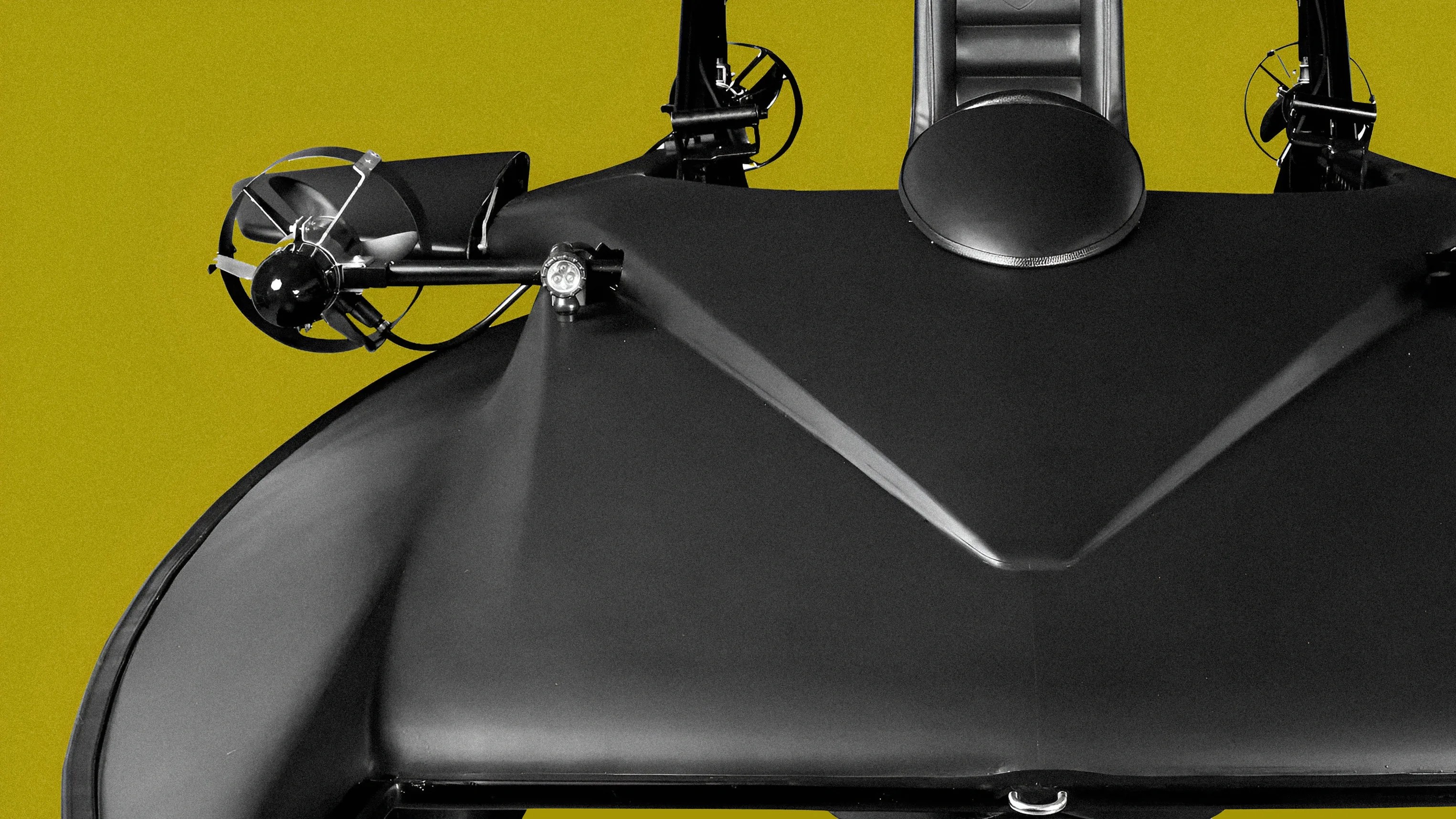 Black streamlined watercraft with dual propellers and a padded seat against a yellow background.