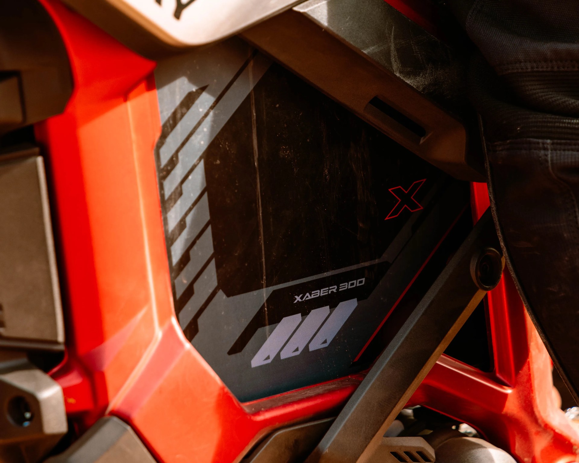 Close-up of a red vehicle frame with a black panel labeled "XABER 300" and a red "X" logo.