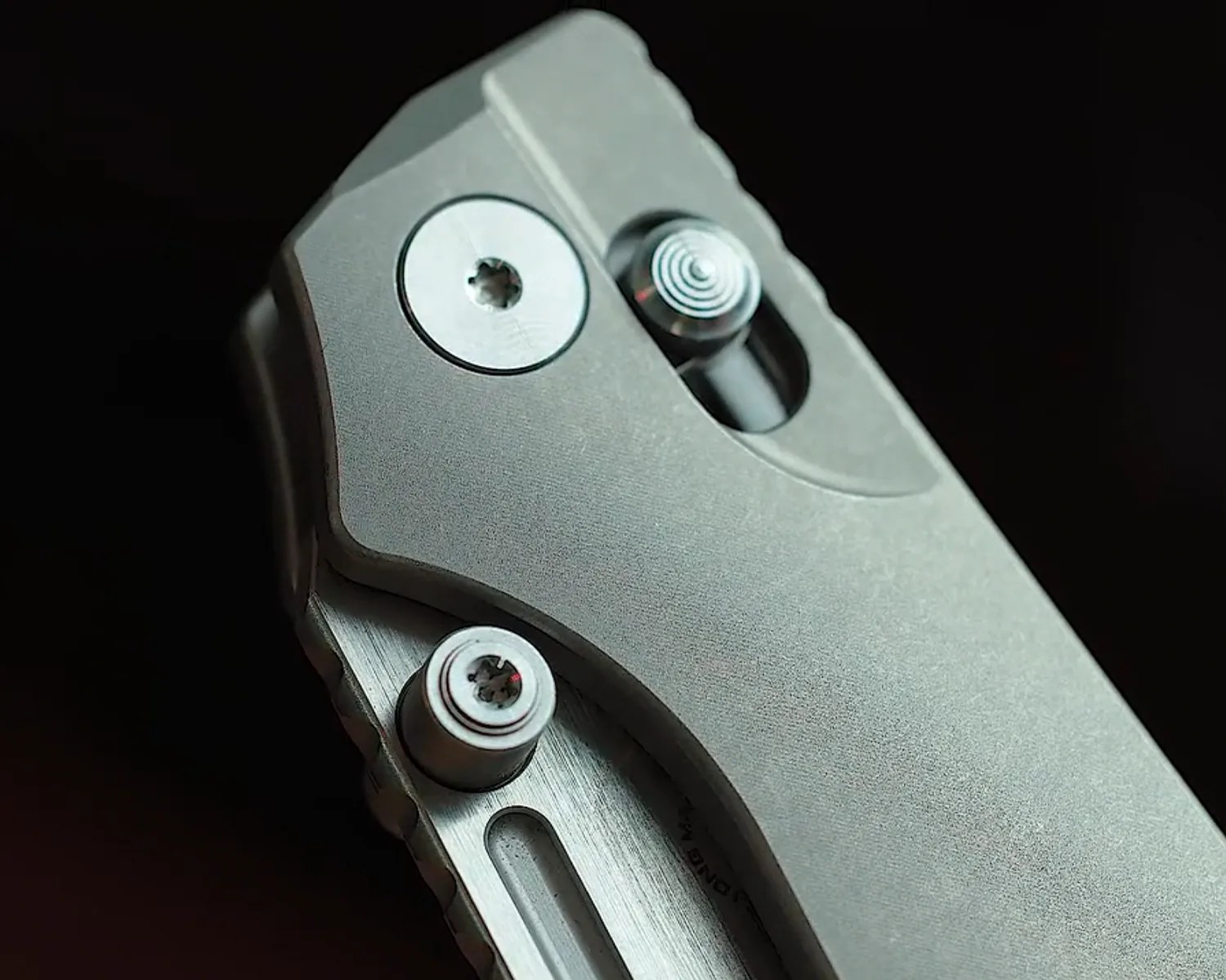 Close-up of a metallic folding knife handle with visible screws and textured surface.