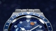 Close-up of a Timex watch with a blue bezel and dial featuring basketball and hand gesture illustrations.