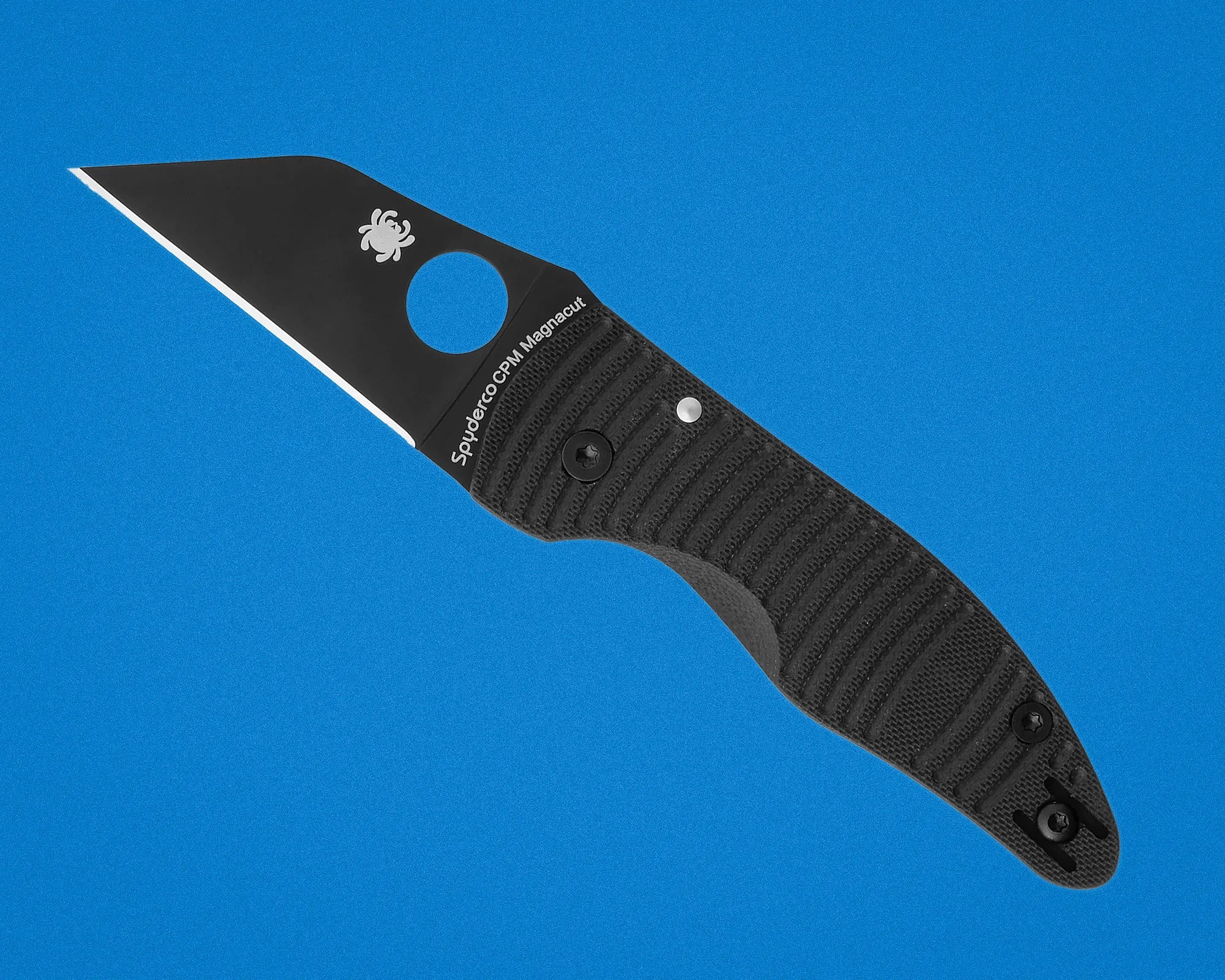Black Spyderco CPM Magnacut knife blade with textured black handle on blue background.