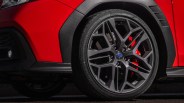 Close-up of a dark gray Subaru alloy wheel with a red brake caliper on a red car.