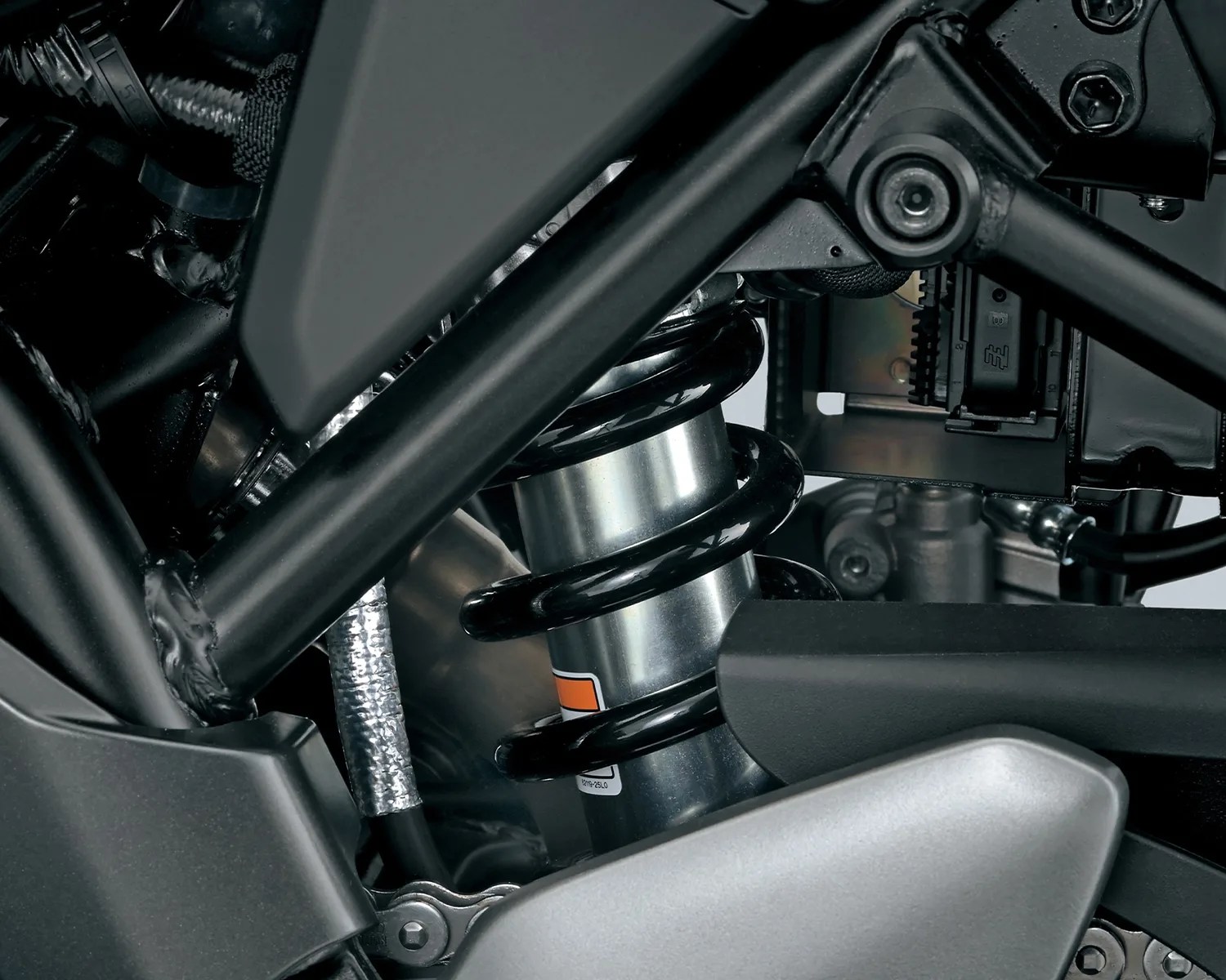 Close-up of a black coil spring shock absorber mounted within a motorcycle frame.