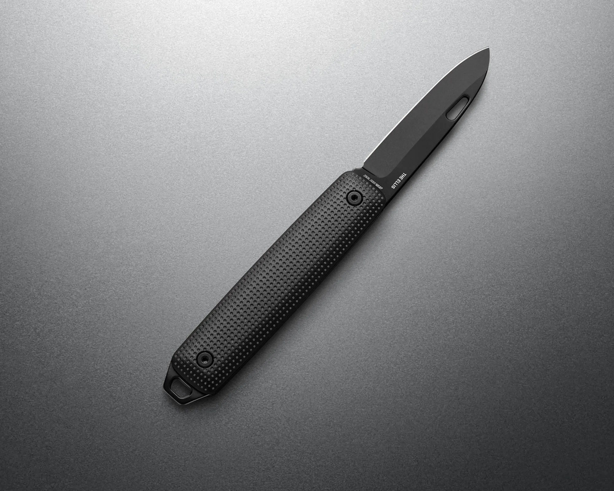Black folding knife with textured handle and partially serrated blade on a gray surface.