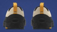 Rear view of beige and black shoes with yellow pull tabs and Vibram logo on the sole against a blue background.