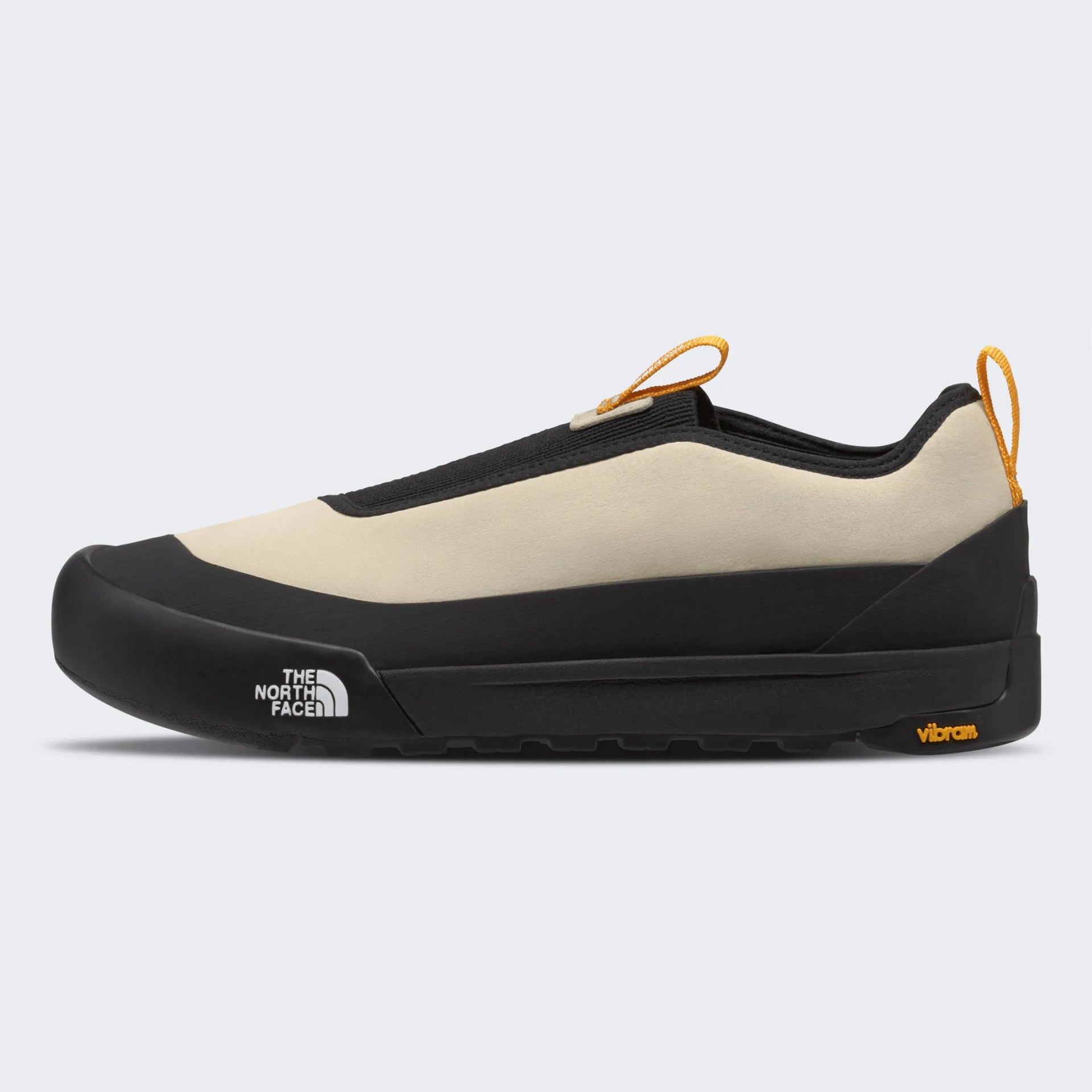 Beige and black slip-on shoe with orange pull tabs, The North Face logo on the side, and Vibram sole branding.