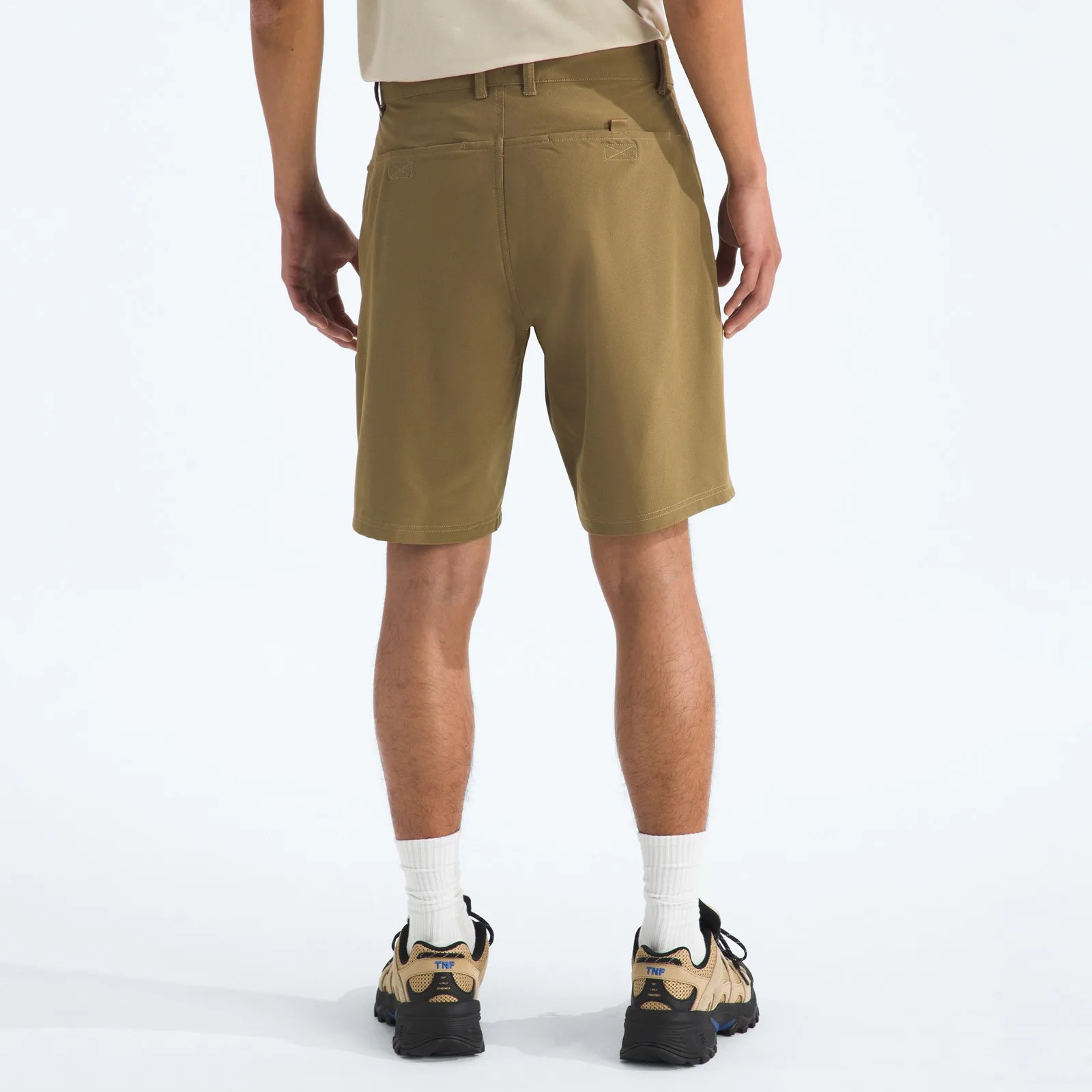 Brown knee-length shorts with back pockets worn by a person standing on a white background.