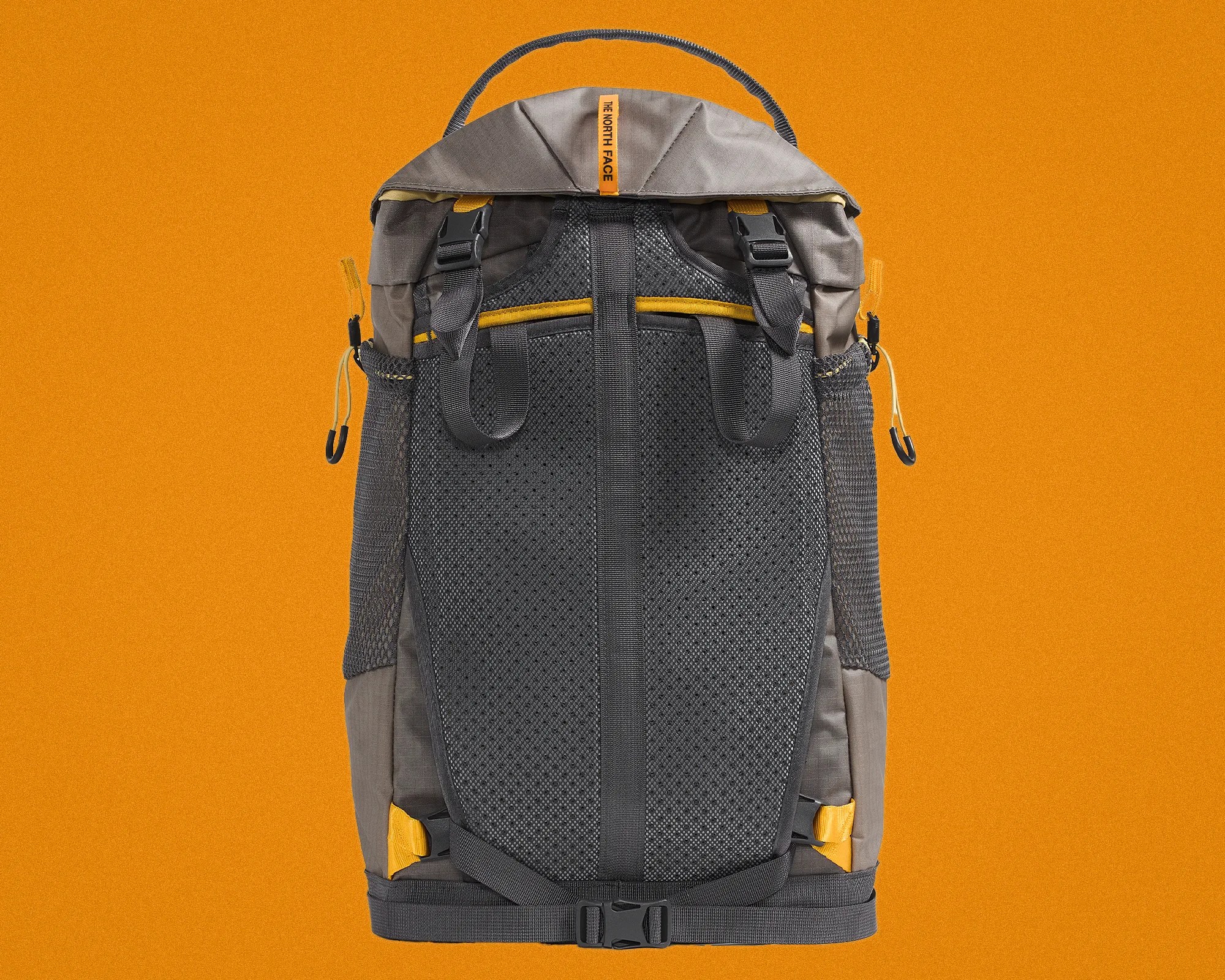 Gray and yellow North Face backpack back panel with padded mesh and adjustable straps on an orange background.