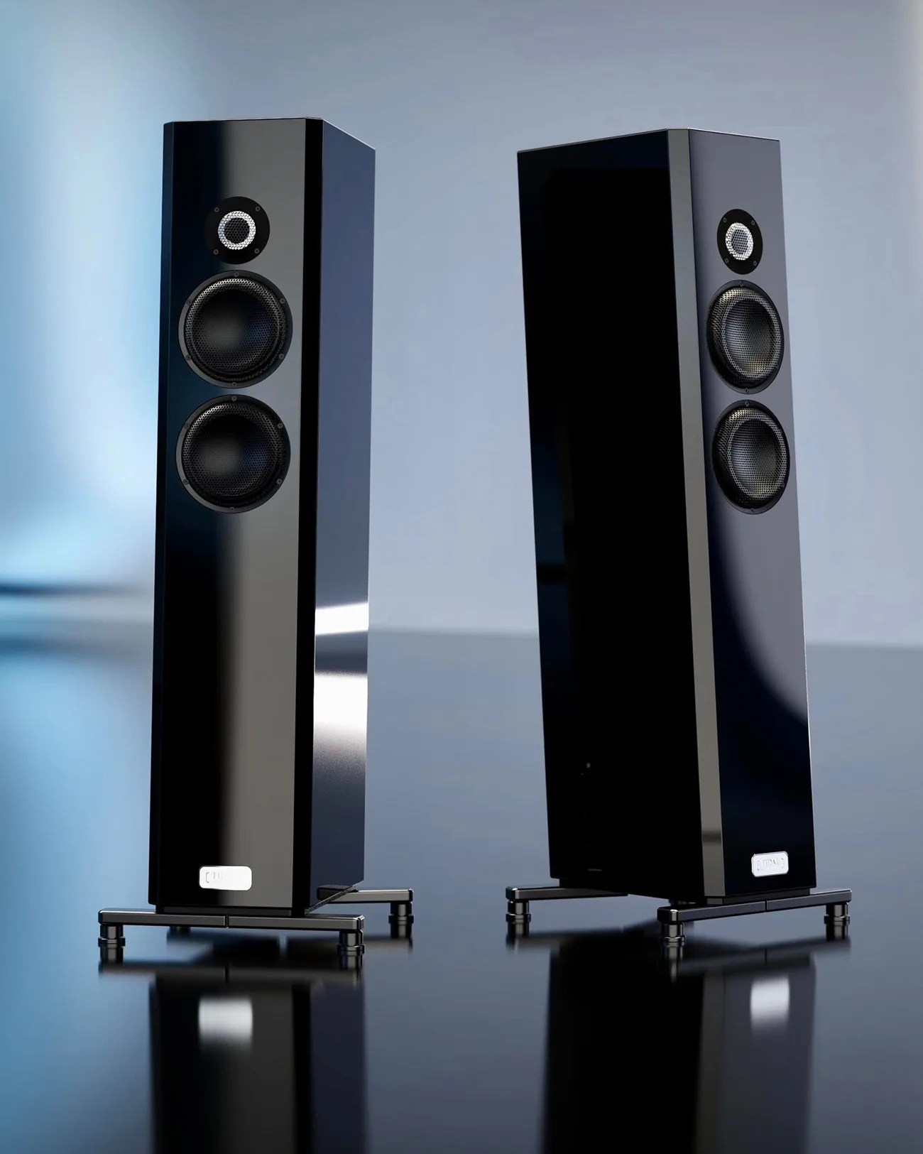 Pair of tall, black glossy floor-standing speakers with three drivers each on metal stands.