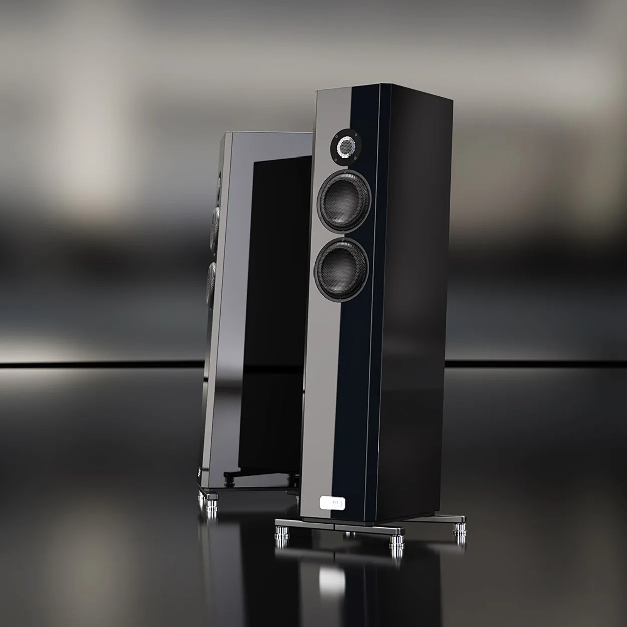 Pair of tall, glossy black floor-standing speakers with two mid-range drivers and one tweeter each on a reflective surface.