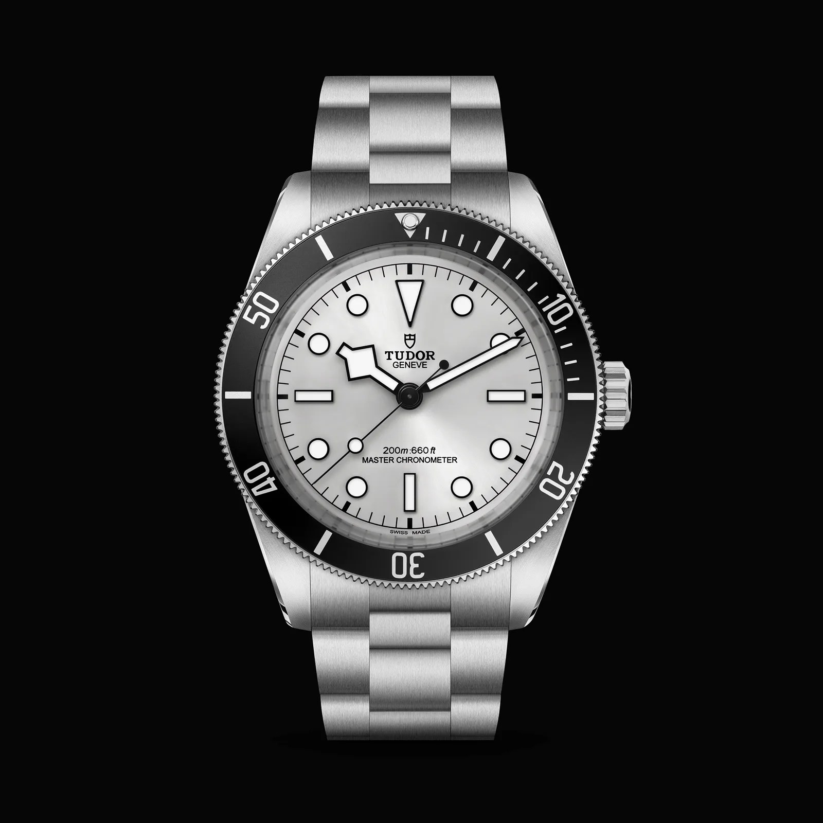 Stainless steel Tudor dive watch with white dial, black bezel, and silver bracelet on black background.