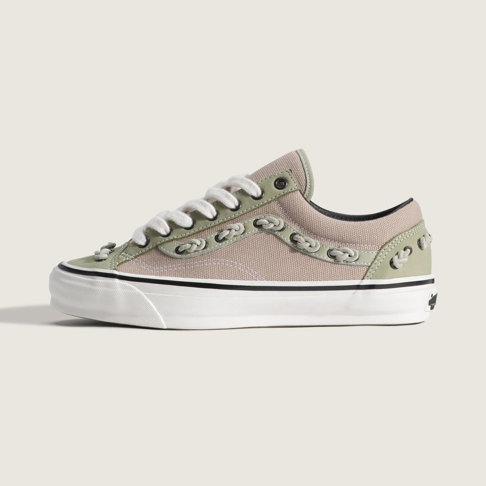 Beige and light green canvas sneaker with white laces and white rubber sole.
