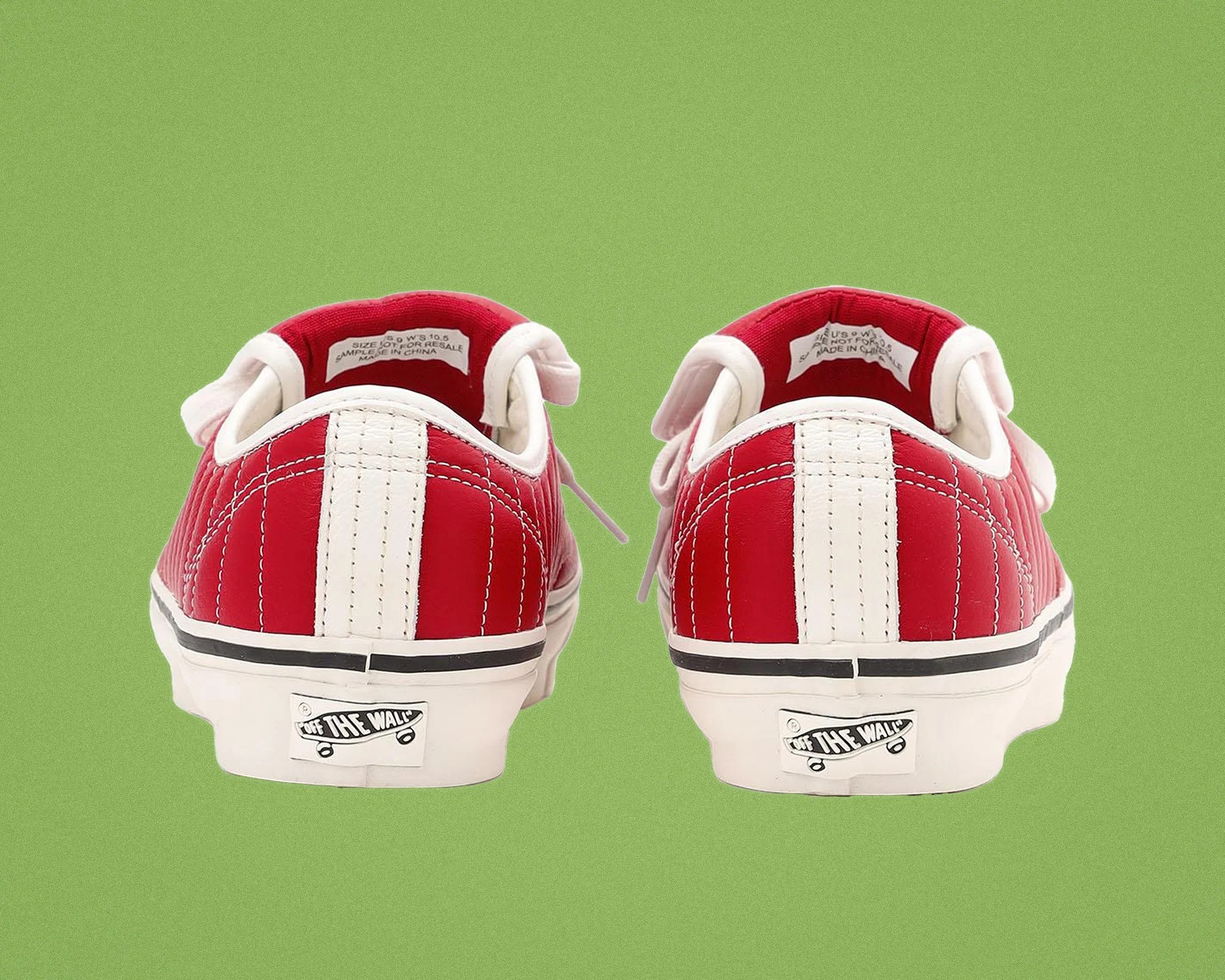 Pair of red Vans sneakers with white vertical stripes and "Off The Wall" logo on the heel against a green background.